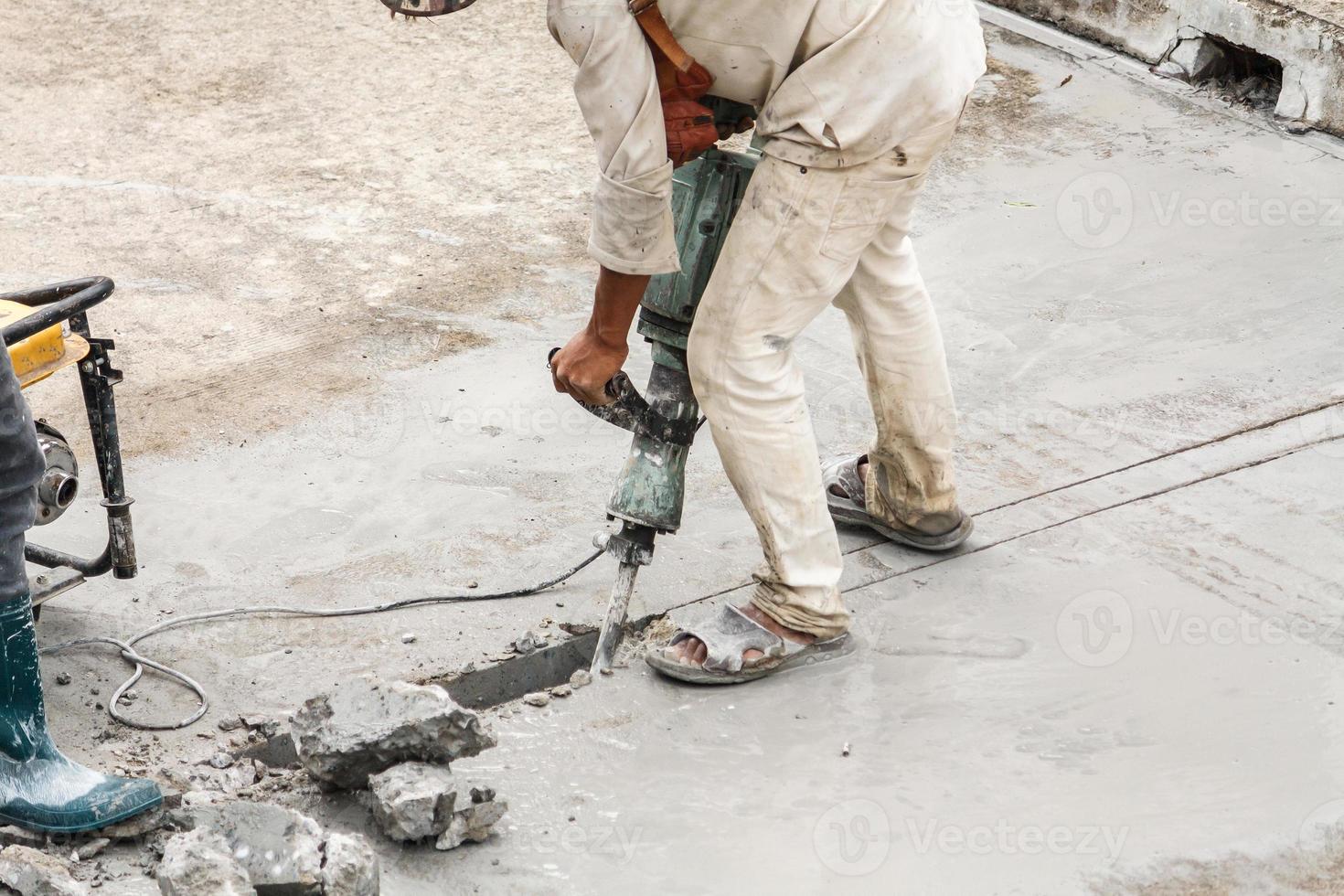 Construction worker using jackhammer drilling concrete surface photo