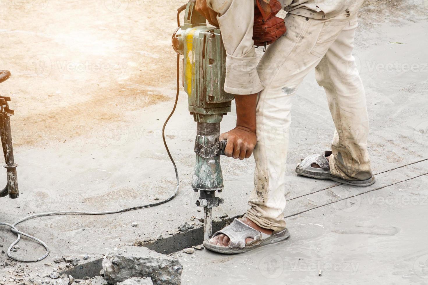 Construction worker using jackhammer drilling concrete surface photo