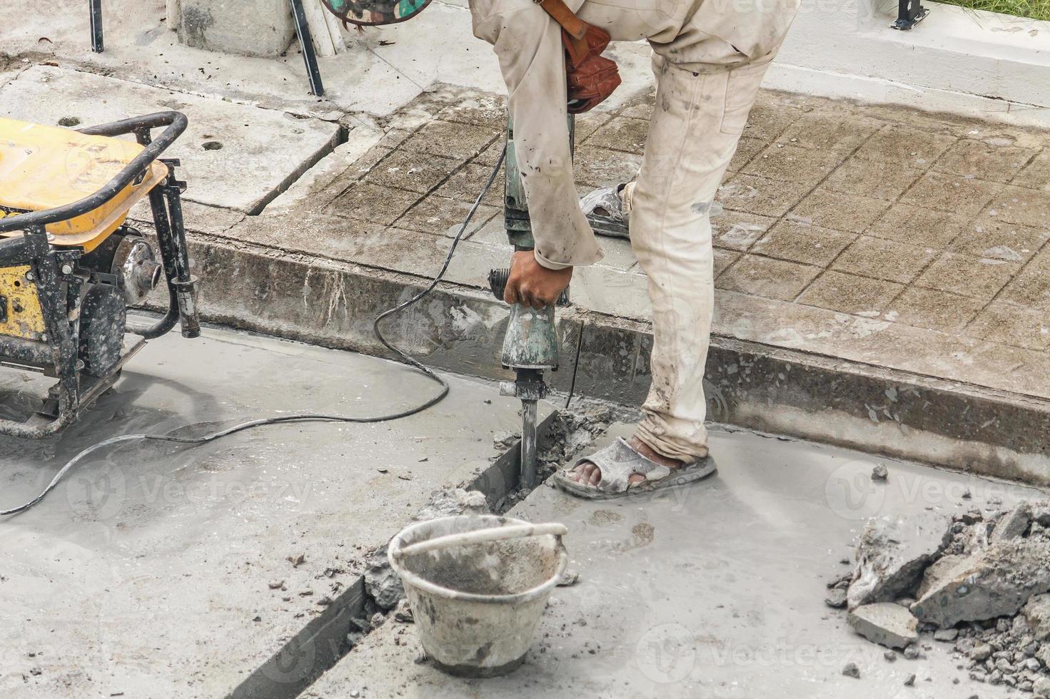 Construction worker using jackhammer drilling concrete surface photo