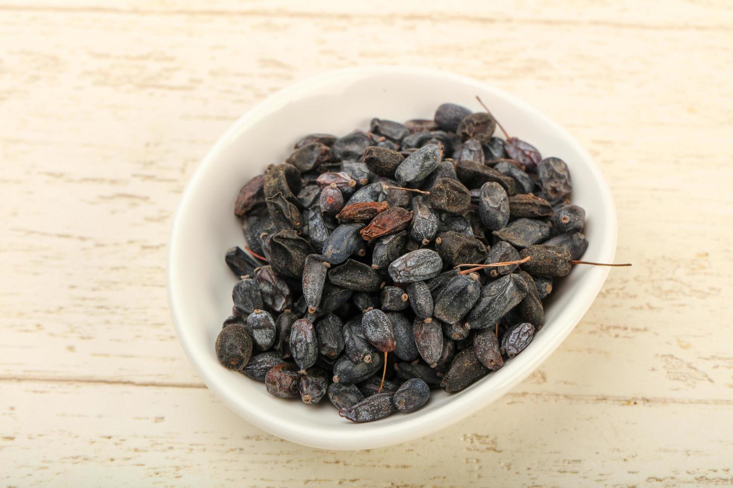 Dry barberry in a bowl on wooden background photo