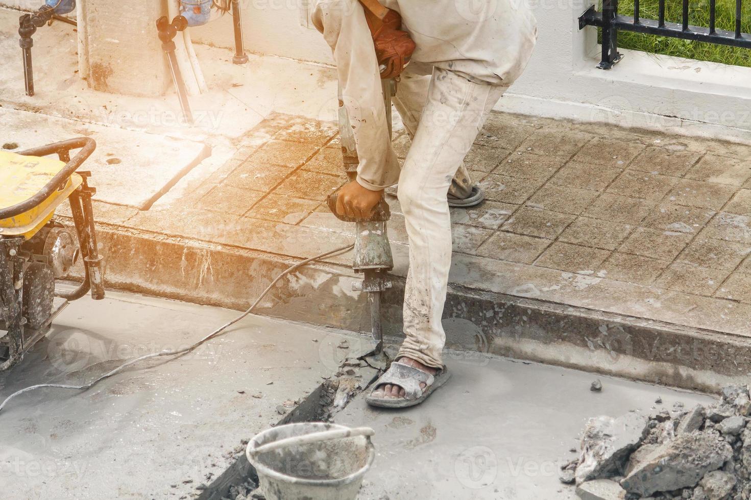 Construction worker using jackhammer drilling concrete surface photo