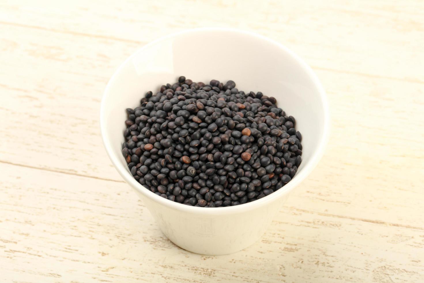Black lentils in a bowl on wooden background photo
