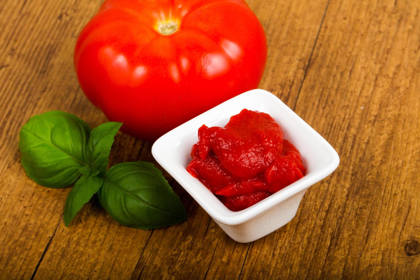 Tomato paste in a bowl on wooden background photo