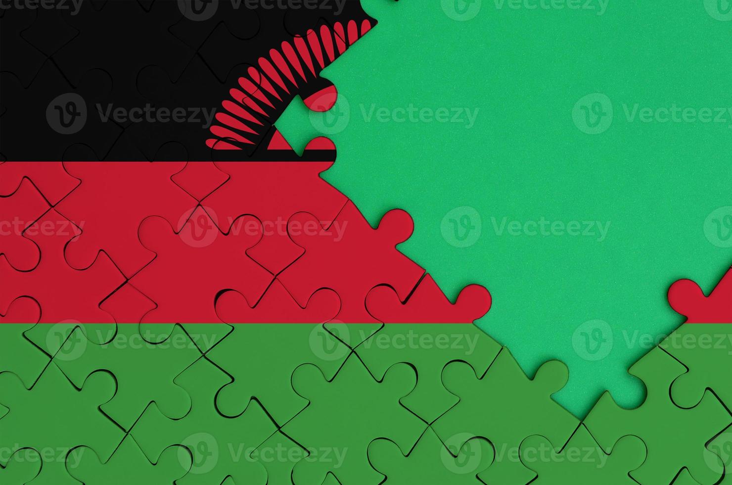 Malawi flag  is depicted on a completed jigsaw puzzle with free green copy space on the right side photo