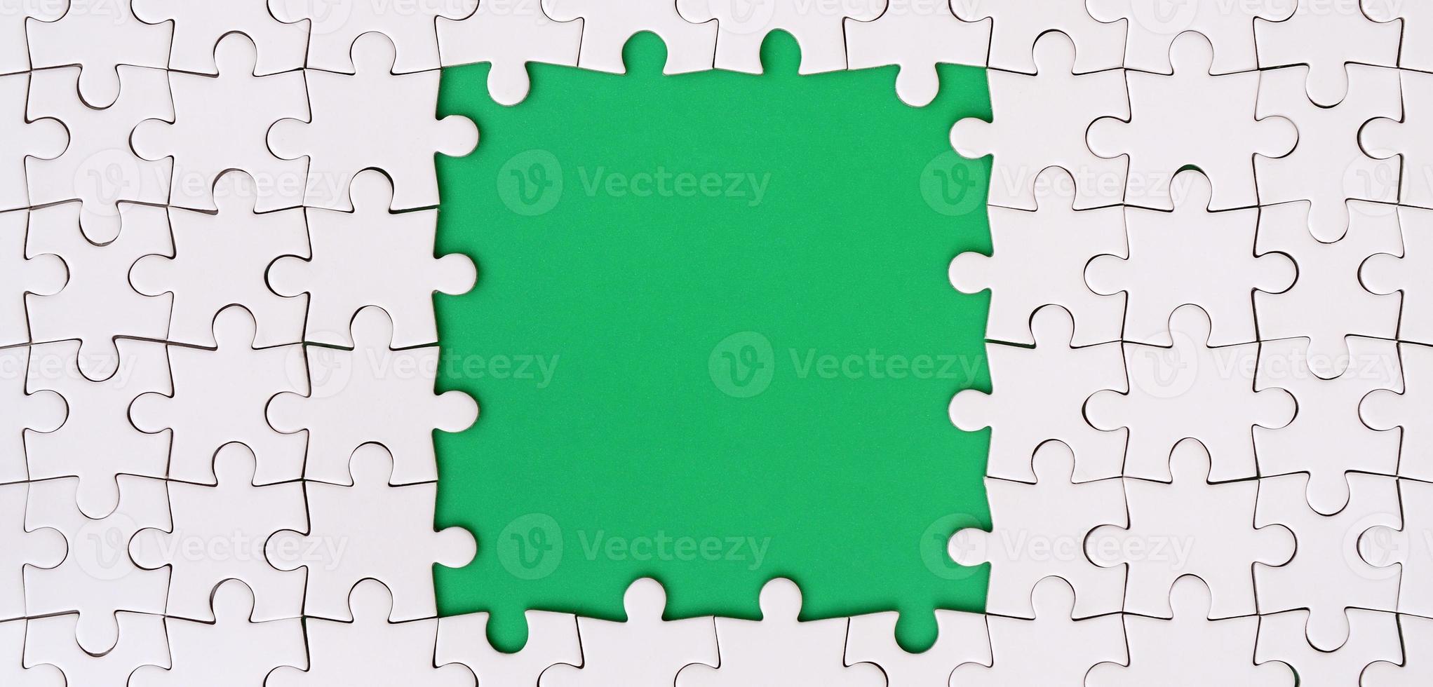 Framing in the form of a rectangle, made of a white jigsaw puzzle around the green space photo