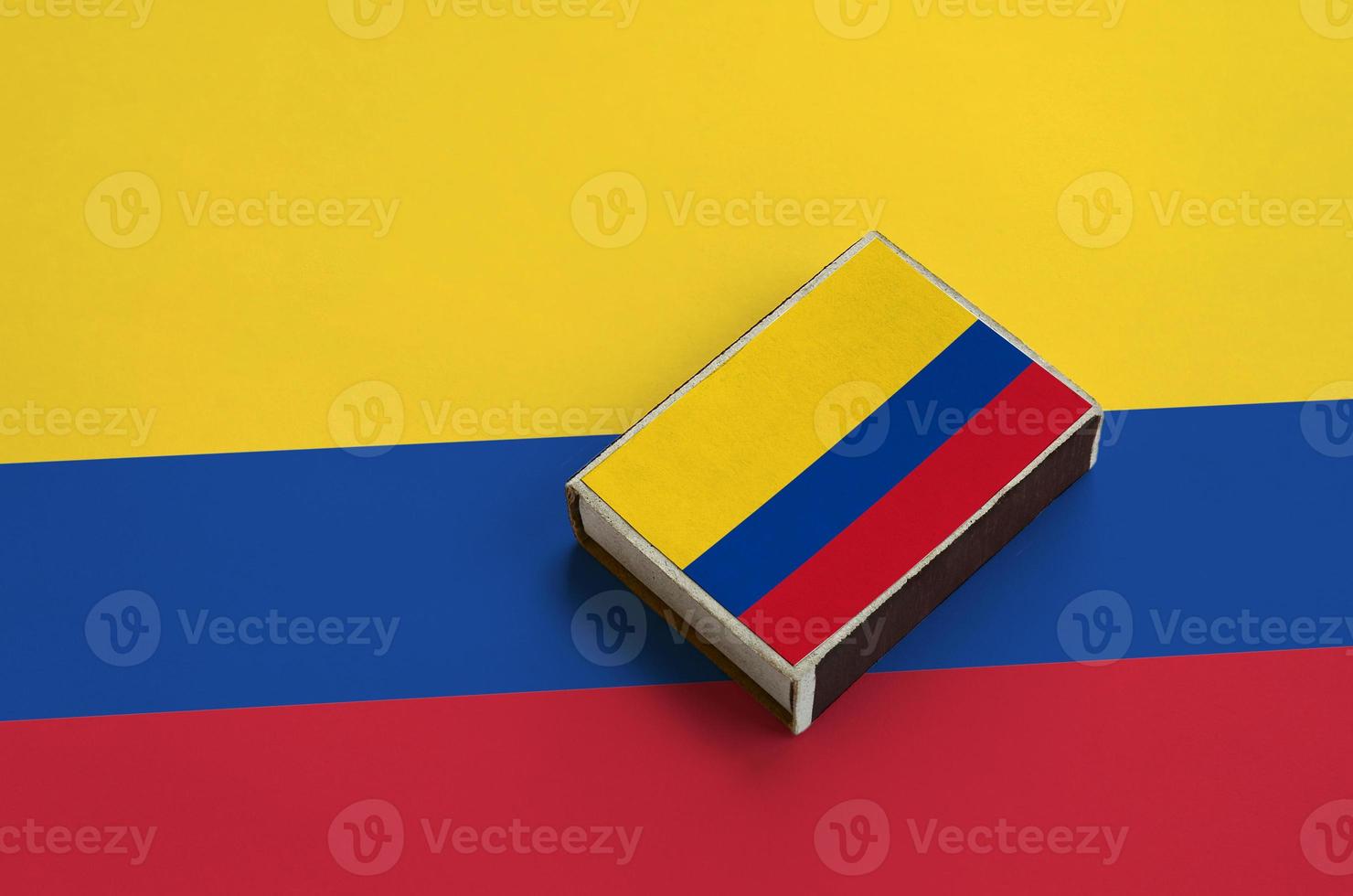 Colombia flag  is pictured on a matchbox that lies on a large flag photo