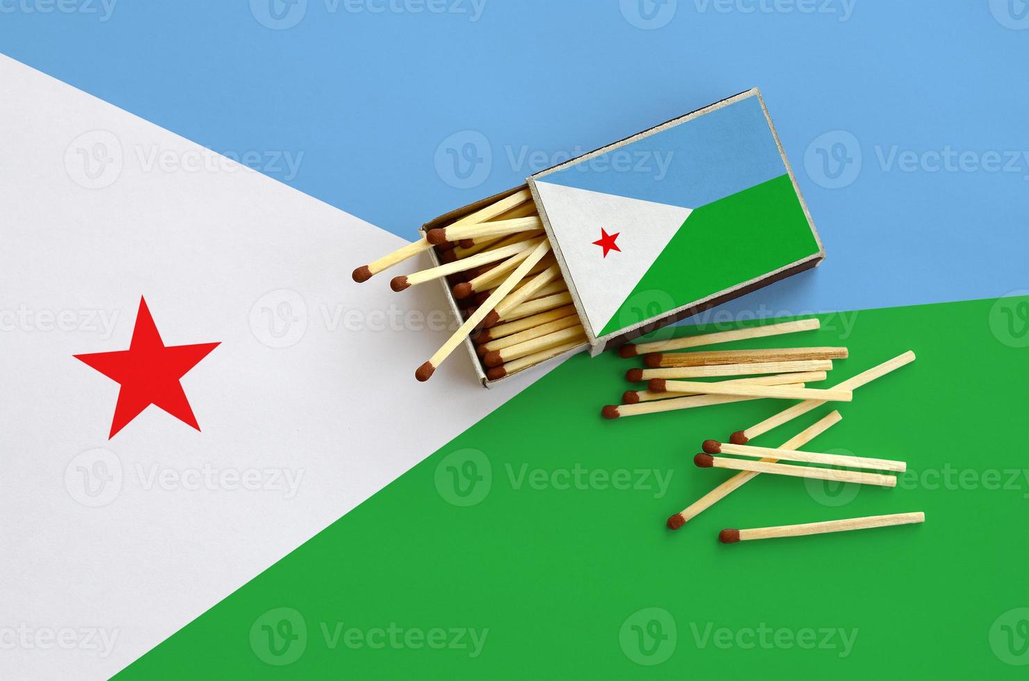 Djibouti flag  is shown on an open matchbox, from which several matches fall and lies on a large flag photo