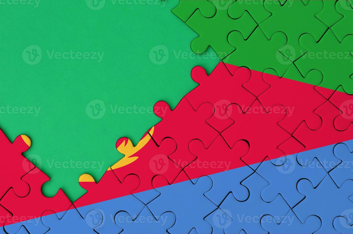 Eritrea flag  is depicted on a completed jigsaw puzzle with free green copy space on the left side photo