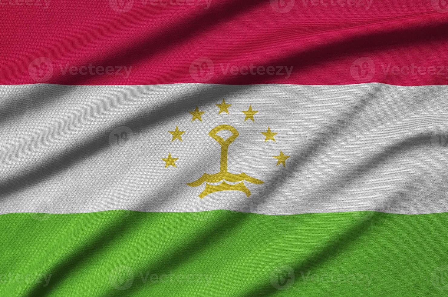 Tajikistan flag  is depicted on a sports cloth fabric with many folds. Sport team banner photo