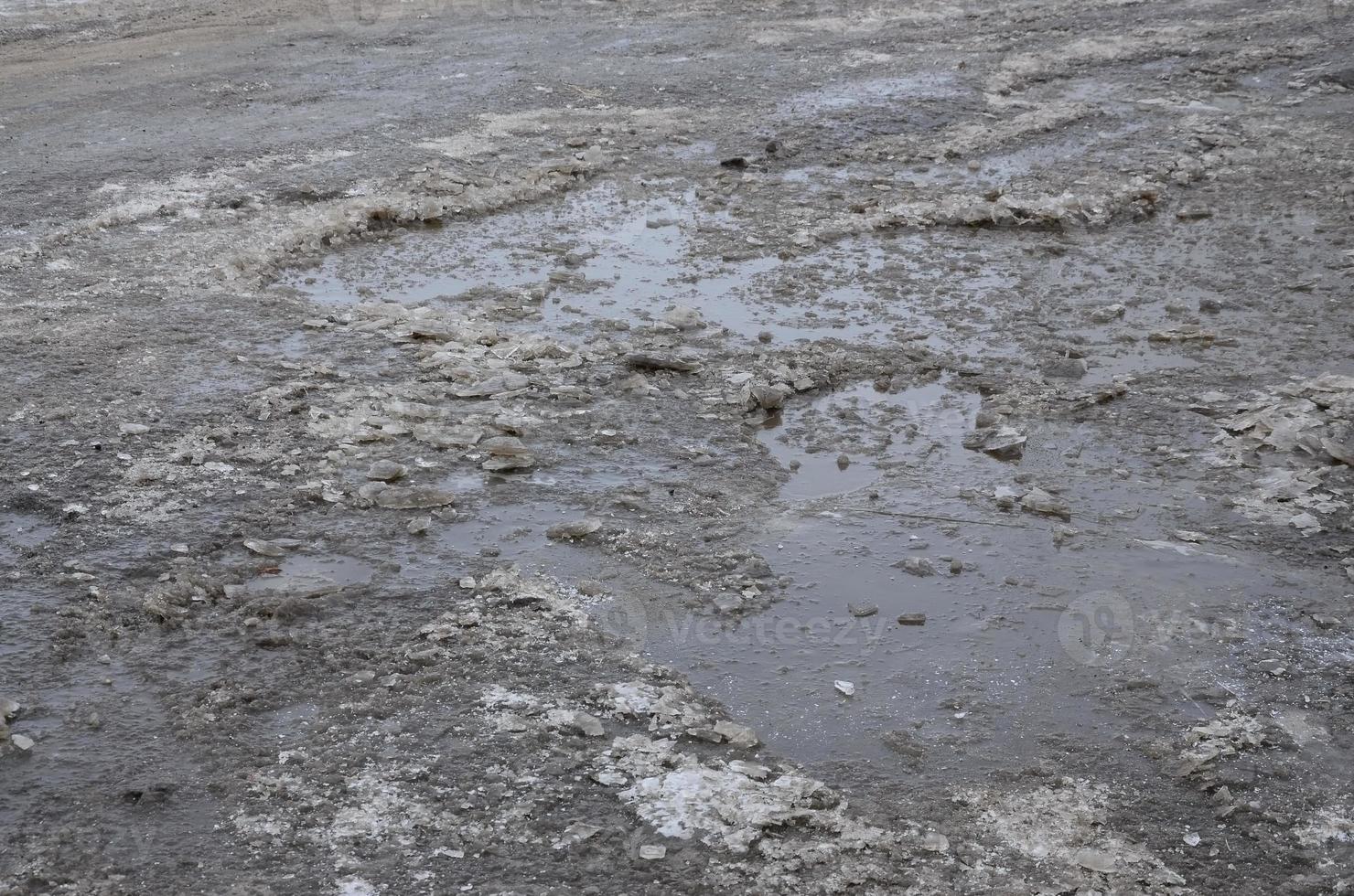 Damaged asphalt road with potholes caused by freezing and thawing cycles during the winter. Poor road photo