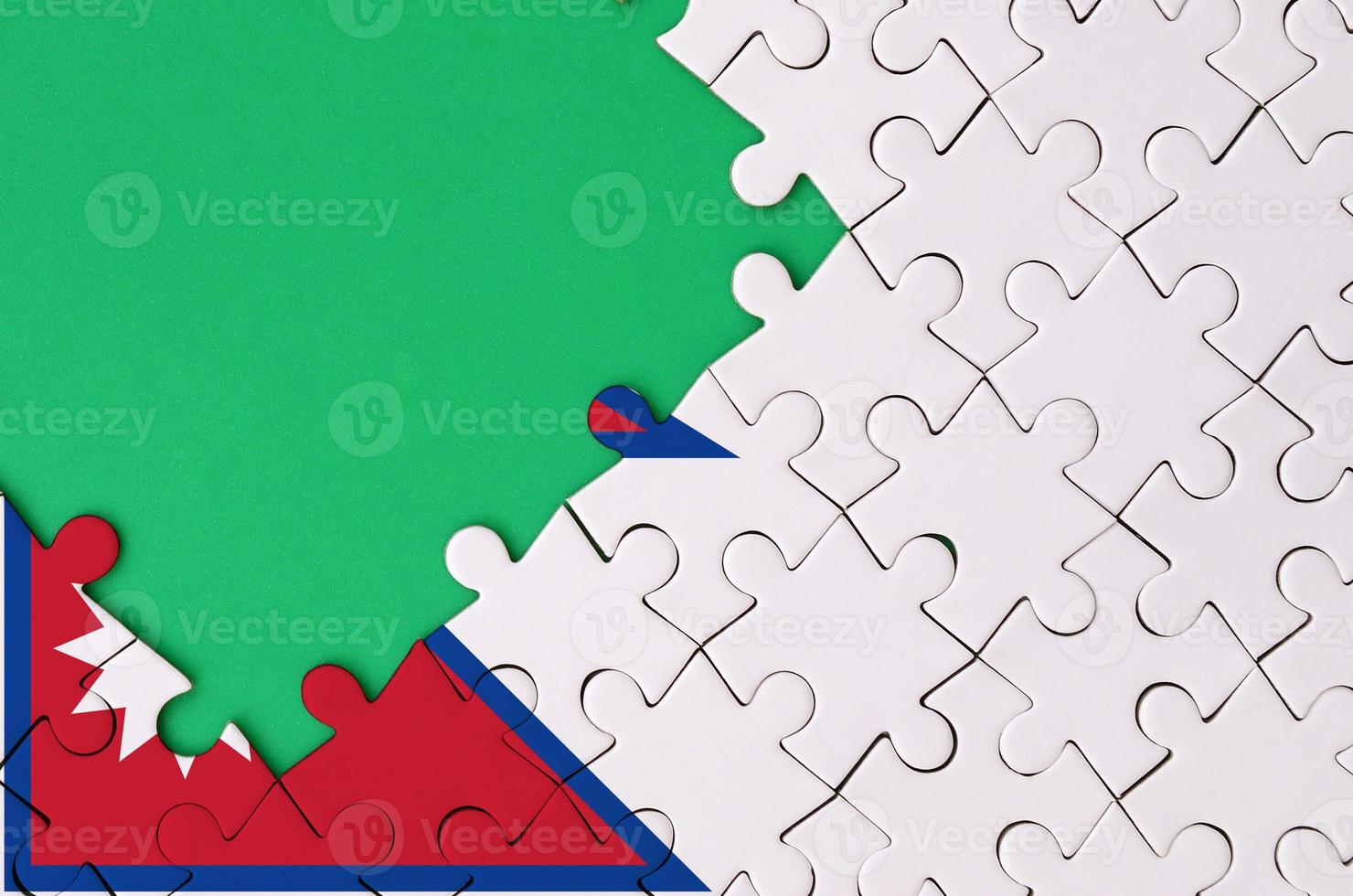 Nepal flag  is depicted on a completed jigsaw puzzle with free green copy space on the left side photo