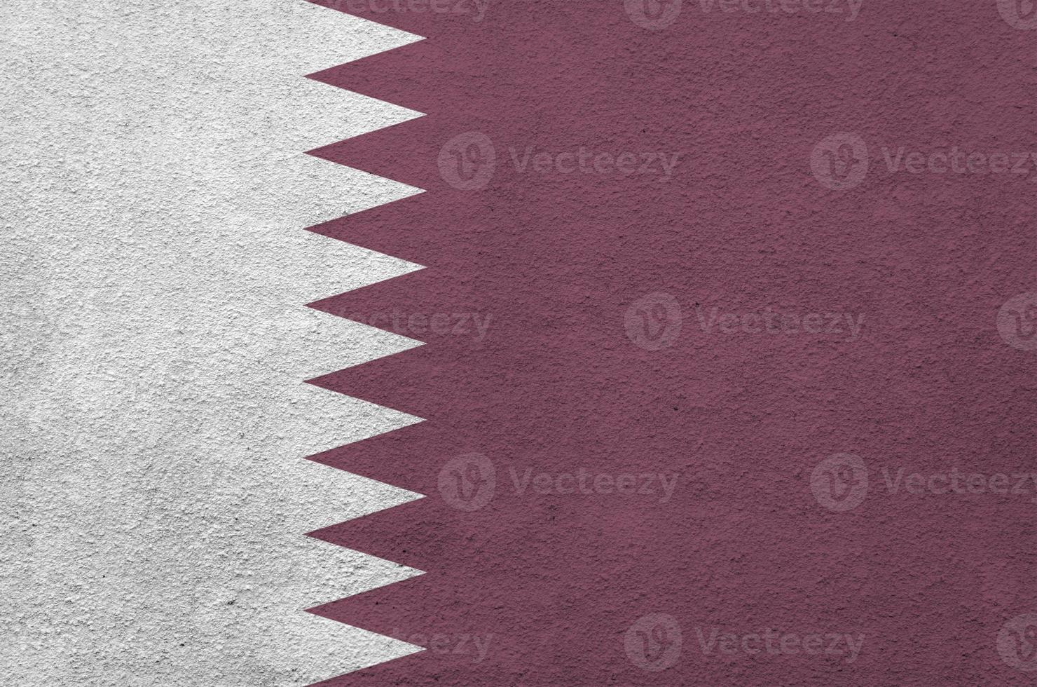 Qatar flag depicted in bright paint colors on old relief plastering wall. Textured banner on rough background photo