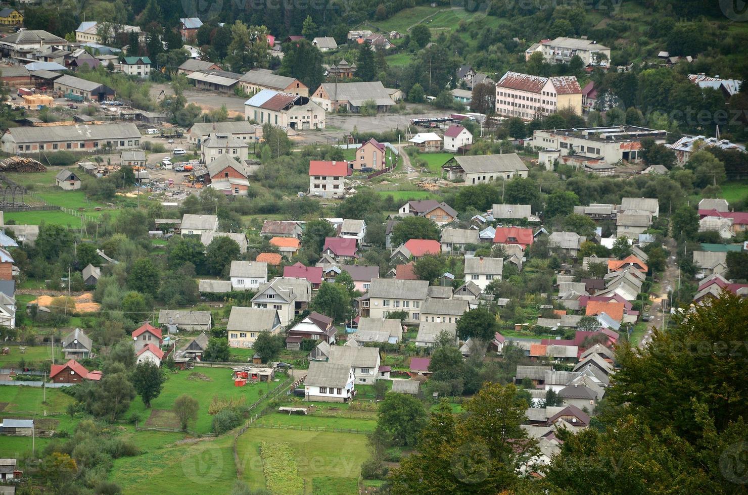 A beautiful view of the village of Mezhgorye, Carpathian region. A lot of residential buildings surrounded by high forest mountains and long river photo