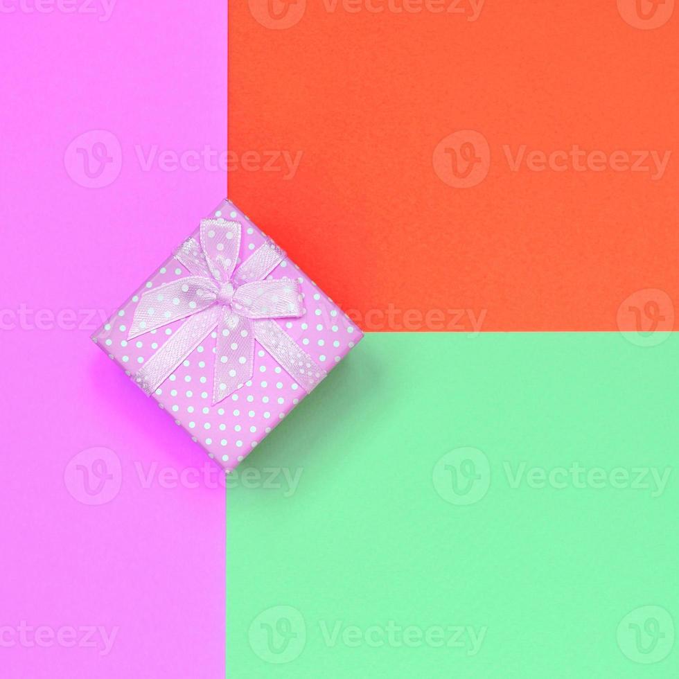 Small pink gift box lie on texture background of fashion pastel turquoise, red and pink colors paper photo