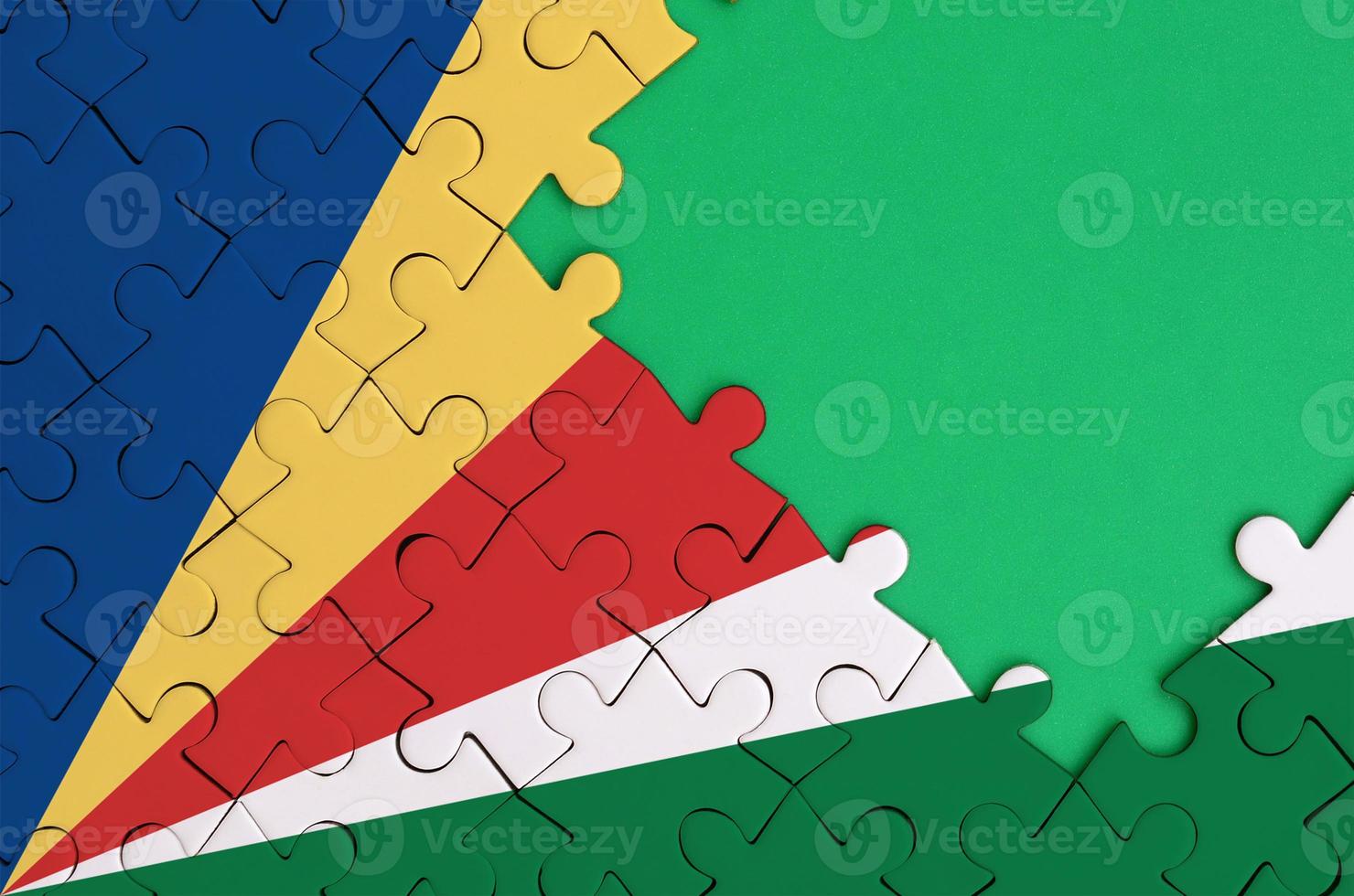 Seychelles flag  is depicted on a completed jigsaw puzzle with free green copy space on the right side photo