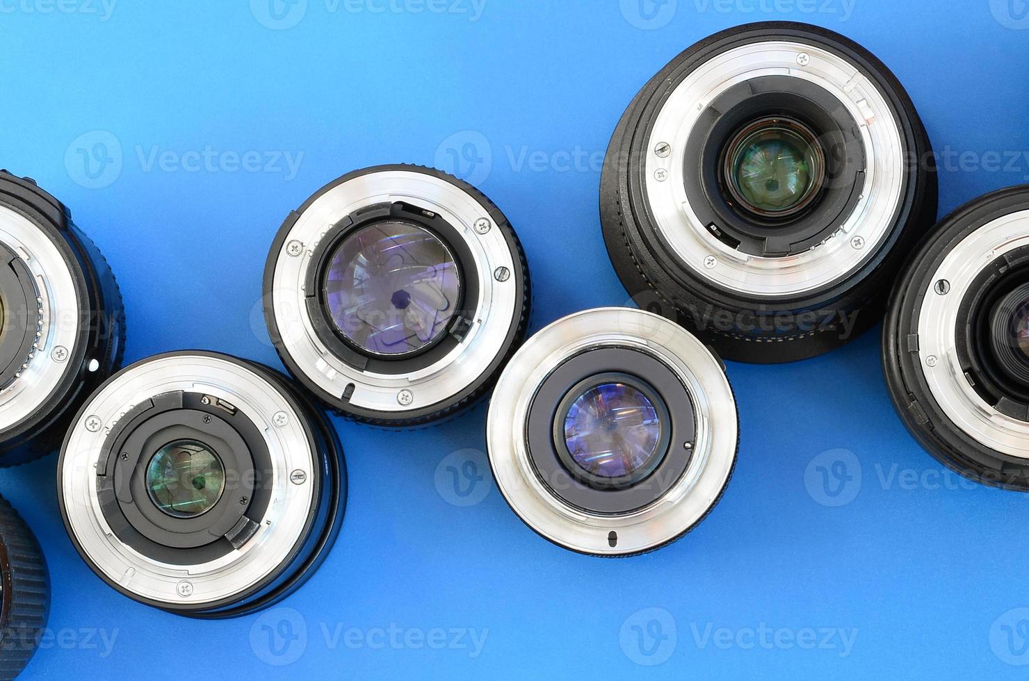 Several photographic lenses lie on a bright blue background. Space for text photo