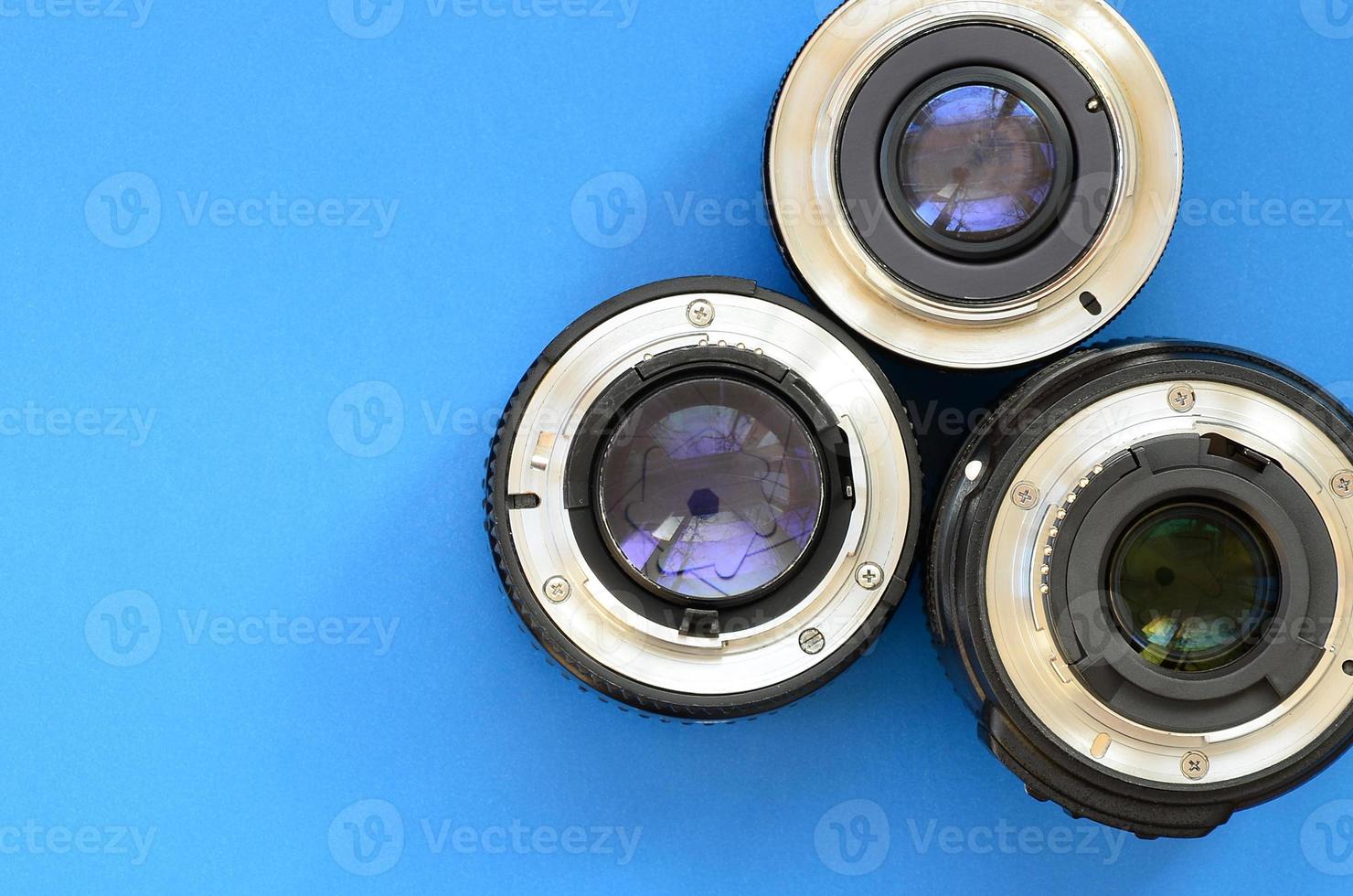Several photographic lenses lie on a bright blue background. Space for text photo