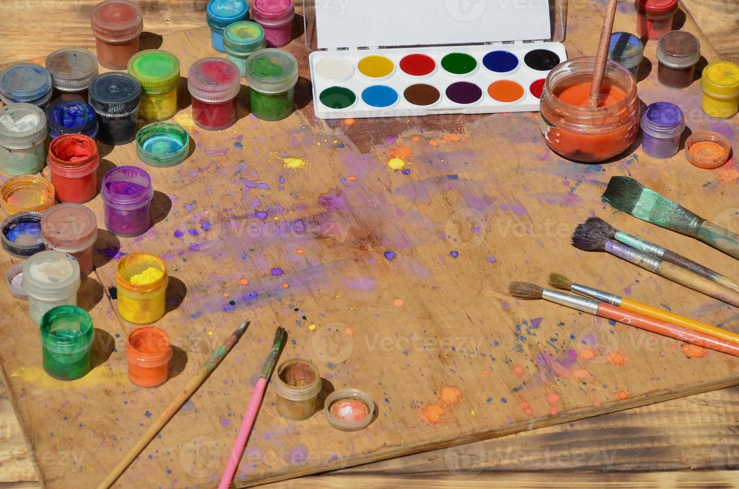 Still life with a lot of brushes and jars of watercolor and gouache paint photo