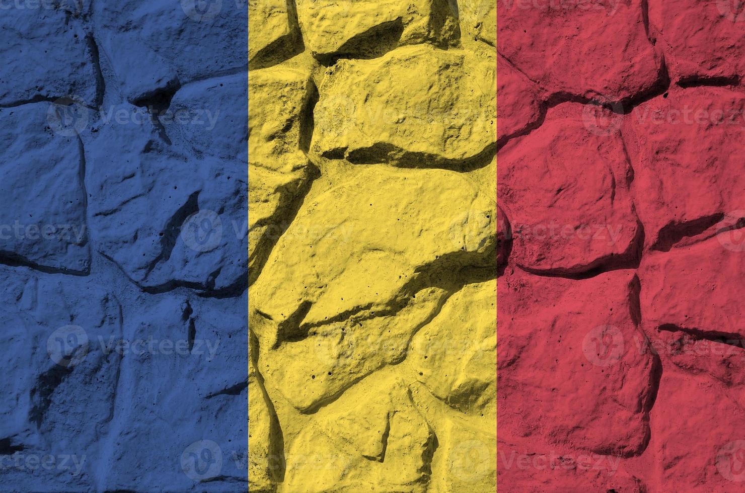 Romania flag depicted in paint colors on old stone wall closeup. Textured banner on rock wall background photo