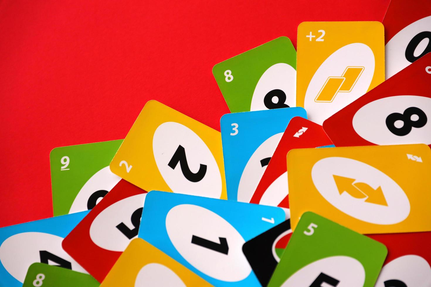 TERNOPIL, UKRAINE - MAY 15, 2022 Many colorful UNO game cards on red background. UNO is an American shedding-type card game that is played with a specially printed deck photo