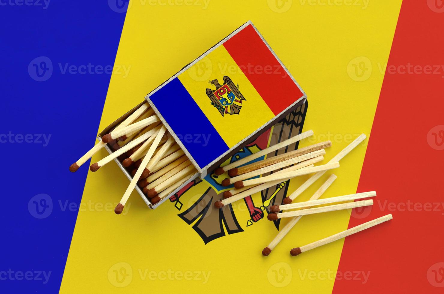 Moldova flag  is shown on an open matchbox, from which several matches fall and lies on a large flag photo