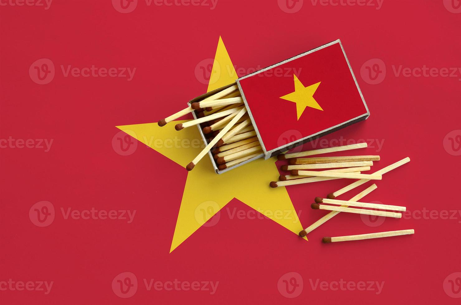 Vietnam flag  is shown on an open matchbox, from which several matches fall and lies on a large flag photo