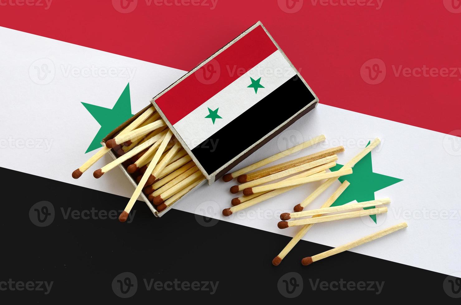 Syria flag  is shown on an open matchbox, from which several matches fall and lies on a large flag photo