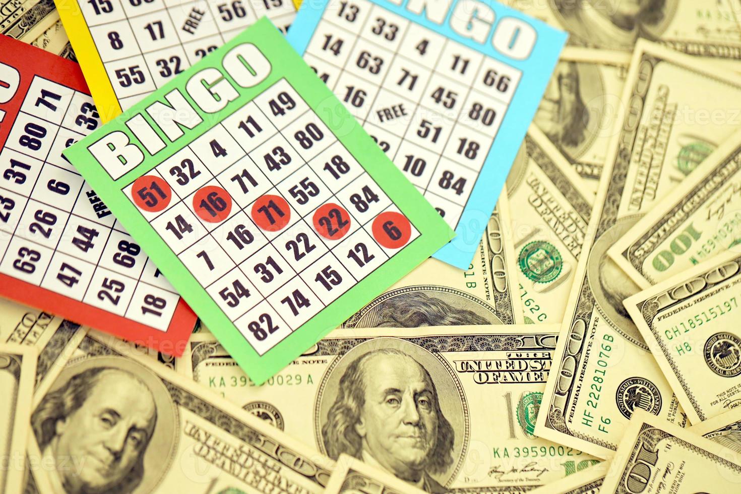 Many bingo boards or playing cards for winning chips and big amount of dollar bills. Classic american or canadian five to five bingo cards on money photo