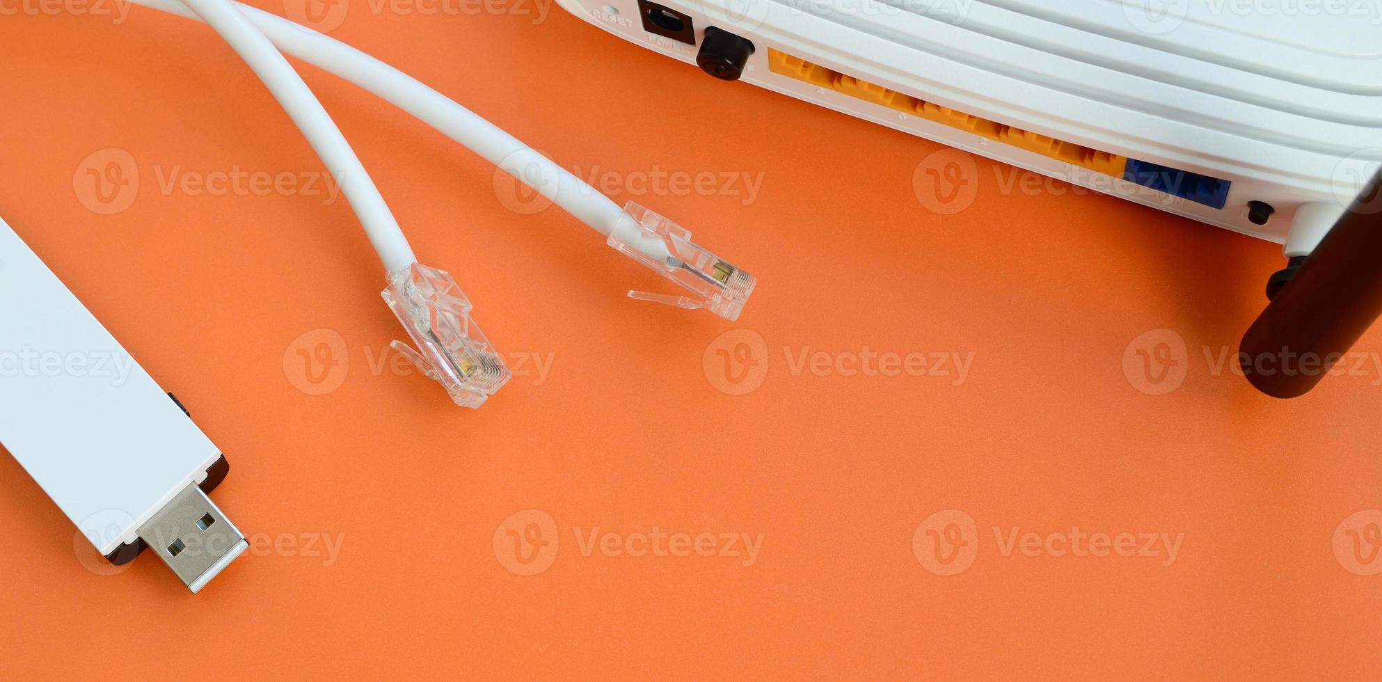 Internet router, portable USB wi-fi adapter and internet cable plugs lie on a bright orange background. Items required for internet connection photo