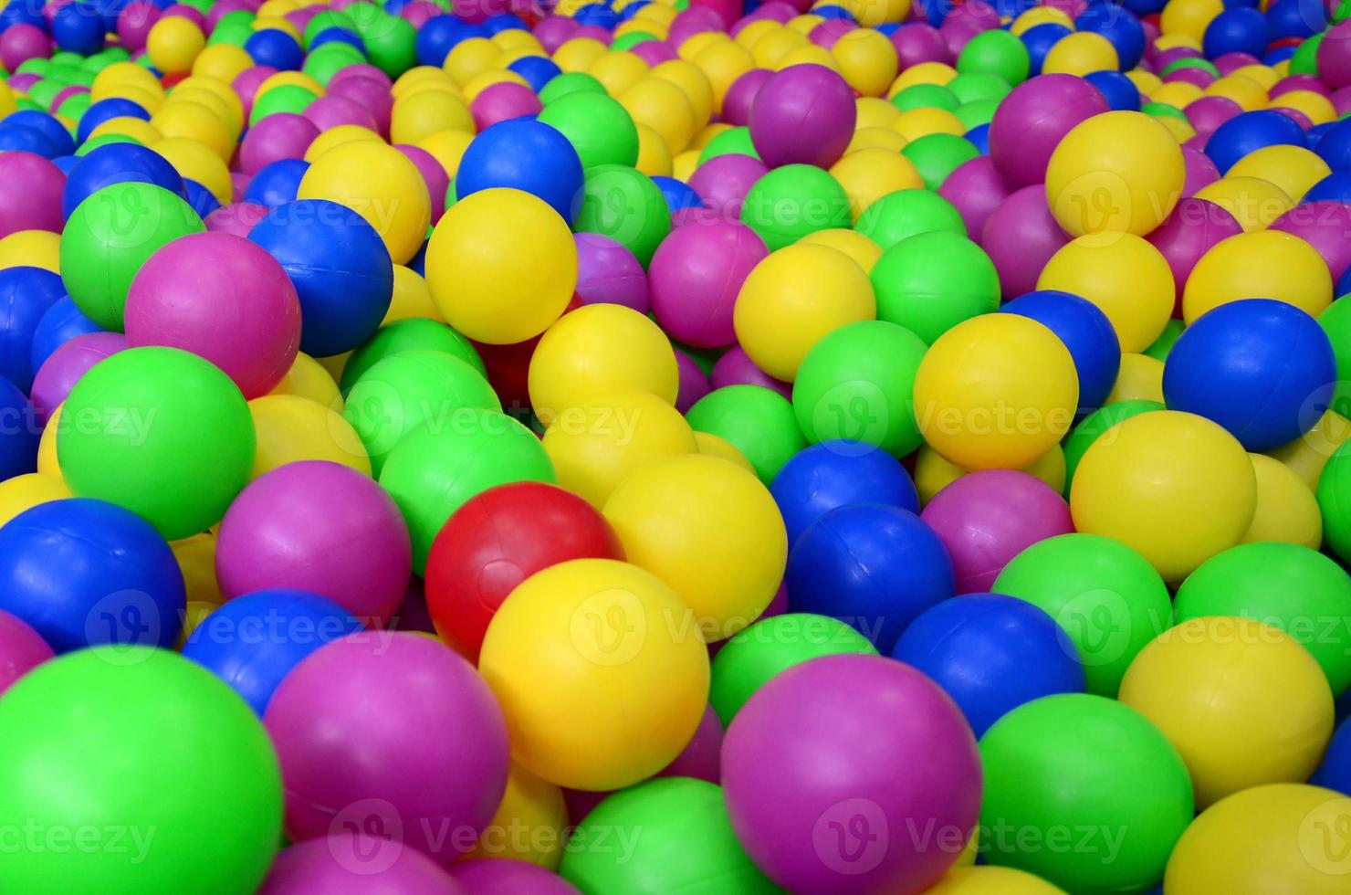Many colorful plastic balls in a kids' ballpit at a playground. Close up pattern photo