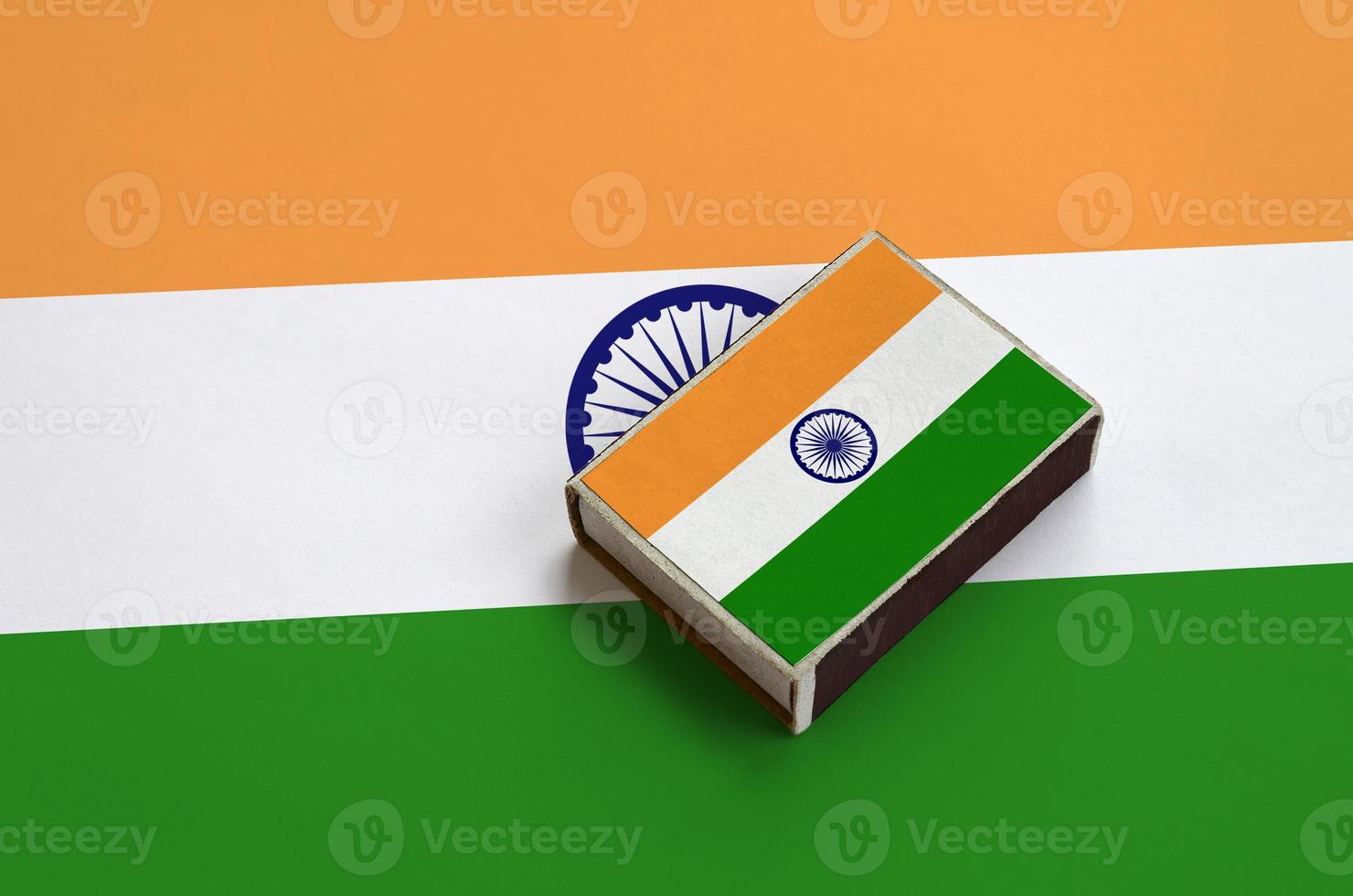 India flag  is pictured on a matchbox that lies on a large flag photo