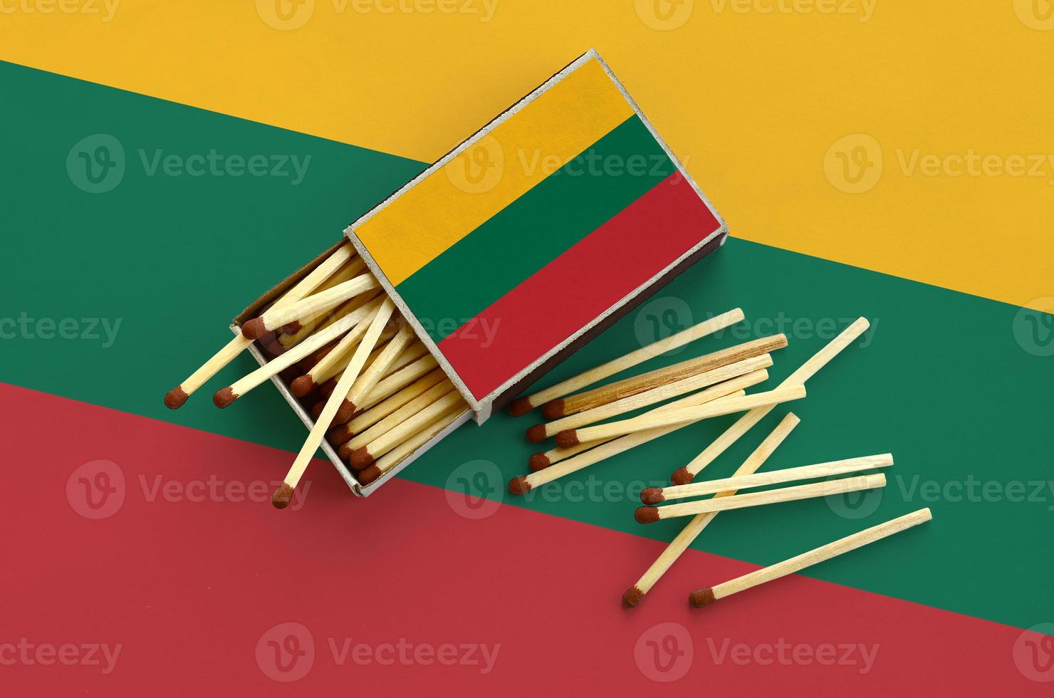 Lithuania flag  is shown on an open matchbox, from which several matches fall and lies on a large flag photo