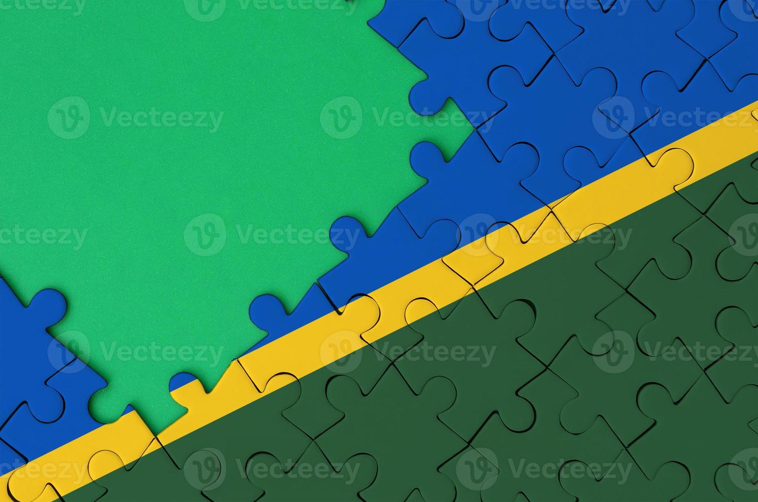 Solomon Islands flag  is depicted on a completed jigsaw puzzle with free green copy space on the left side photo