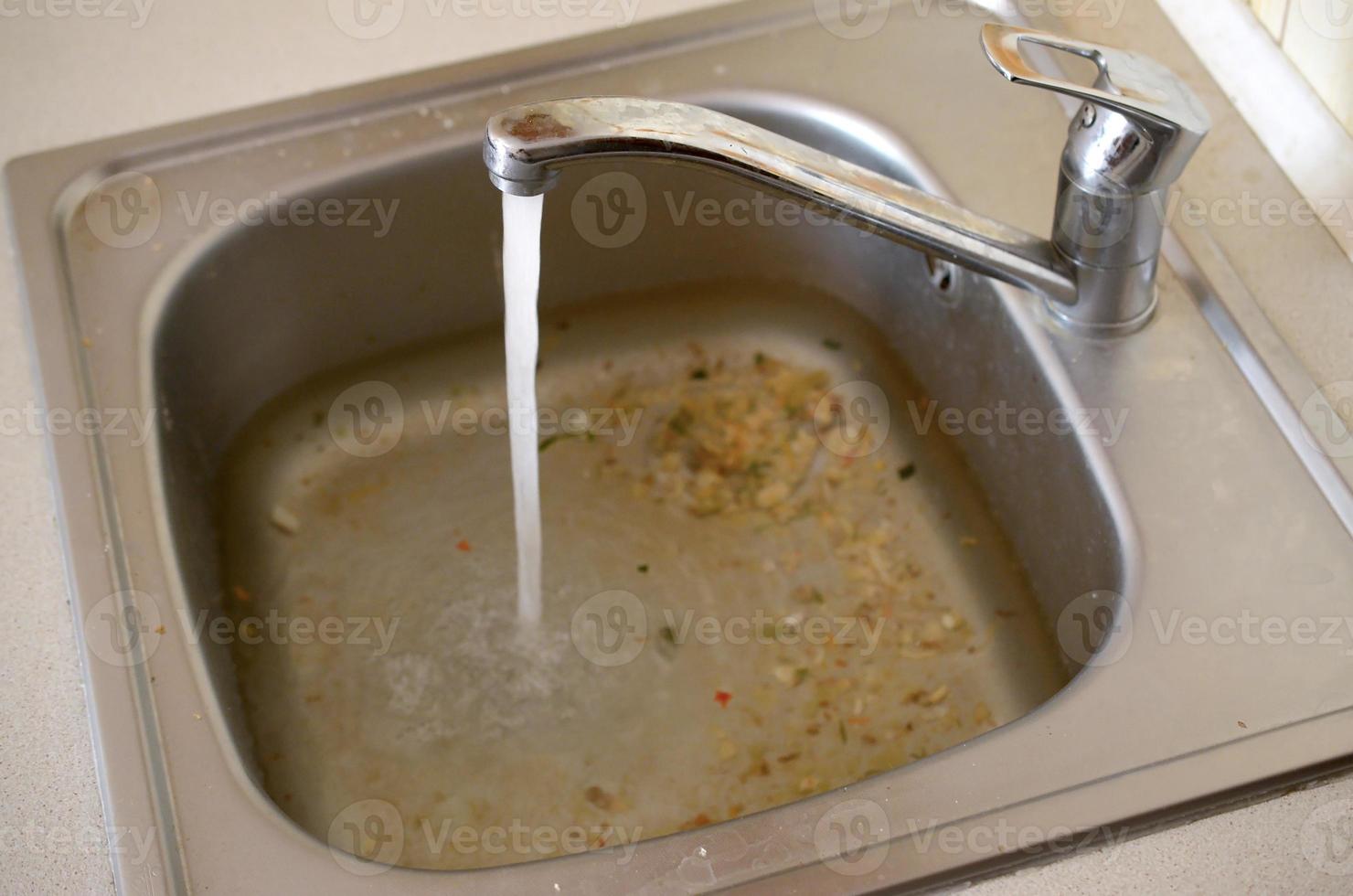 Stainless steel sink plug hole close up full of water and particles of food 12838630 Stock Photo