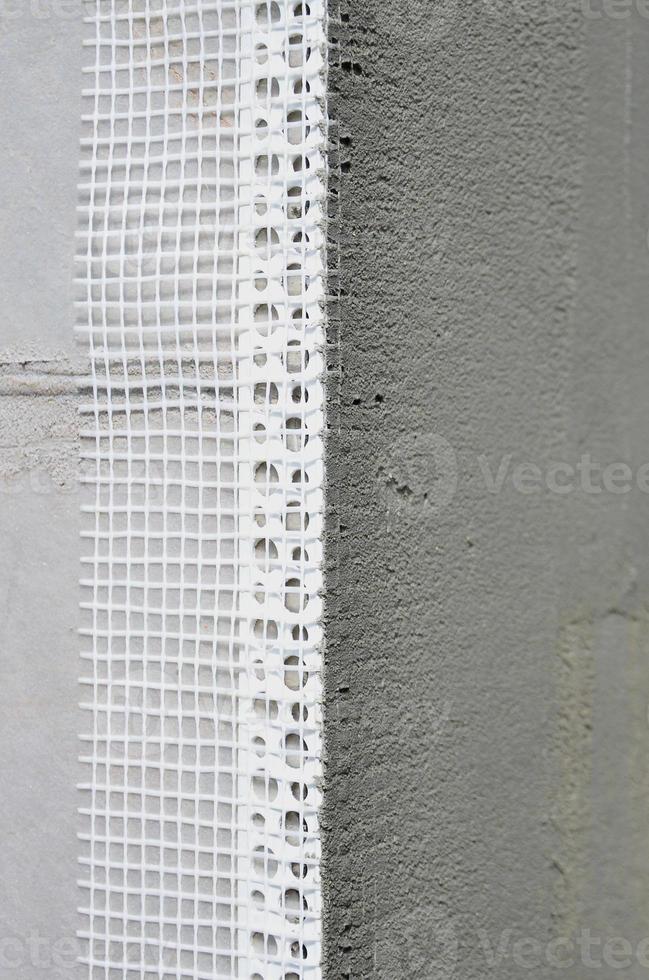 The texture of the wall, covered with gray polystyrene foam plates, which are coated with a reinforcing mixture with a plastic reinforcing profile corner. Stage of wall insulation photo