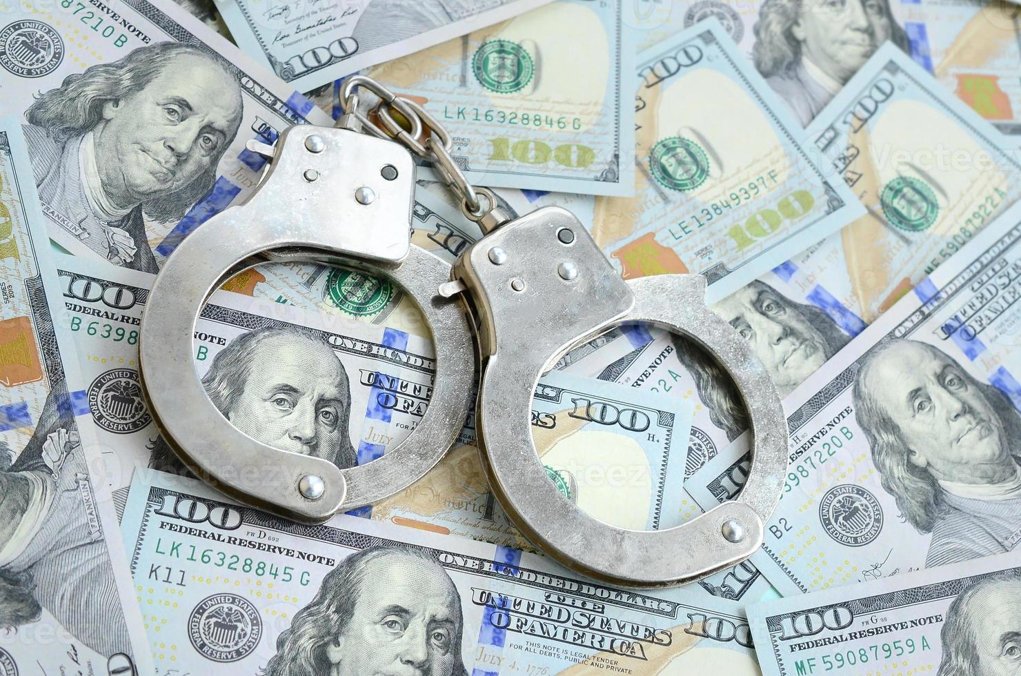 Silver police handcuffs lies on a many dollar bills photo