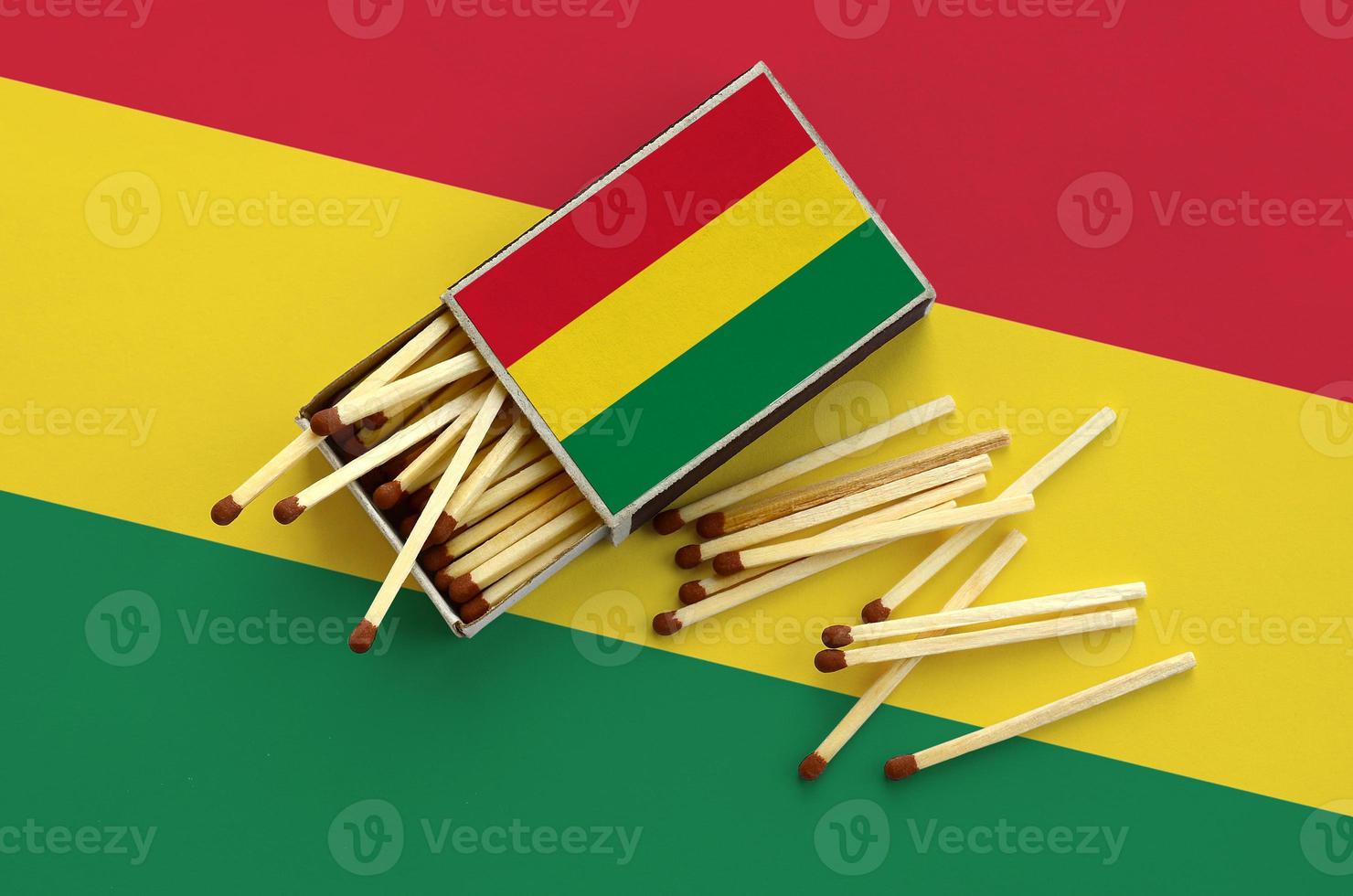 Bolivia flag  is shown on an open matchbox, from which several matches fall and lies on a large flag photo