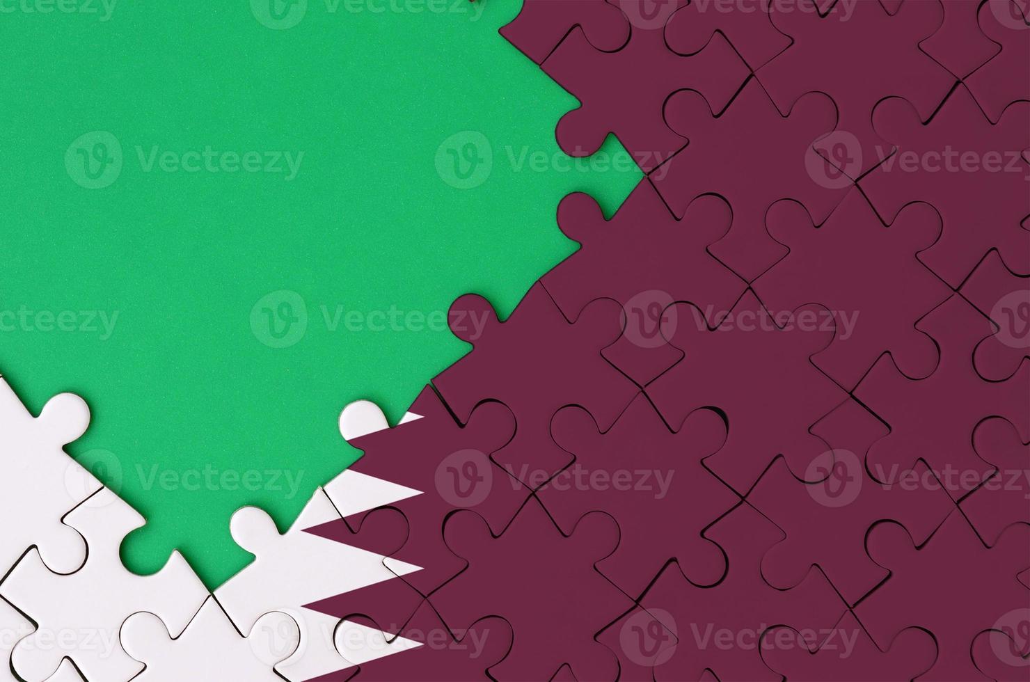 Qatar flag  is depicted on a completed jigsaw puzzle with free green copy space on the left side photo