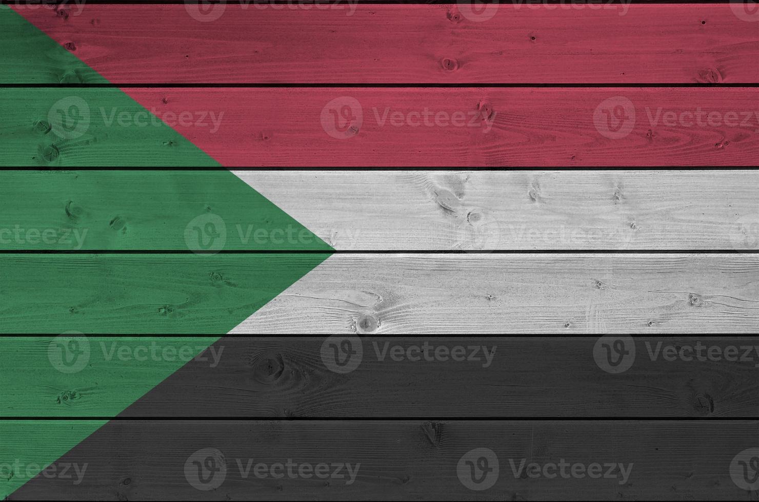 Sudan flag depicted in bright paint colors on old wooden wall. Textured banner on rough background photo