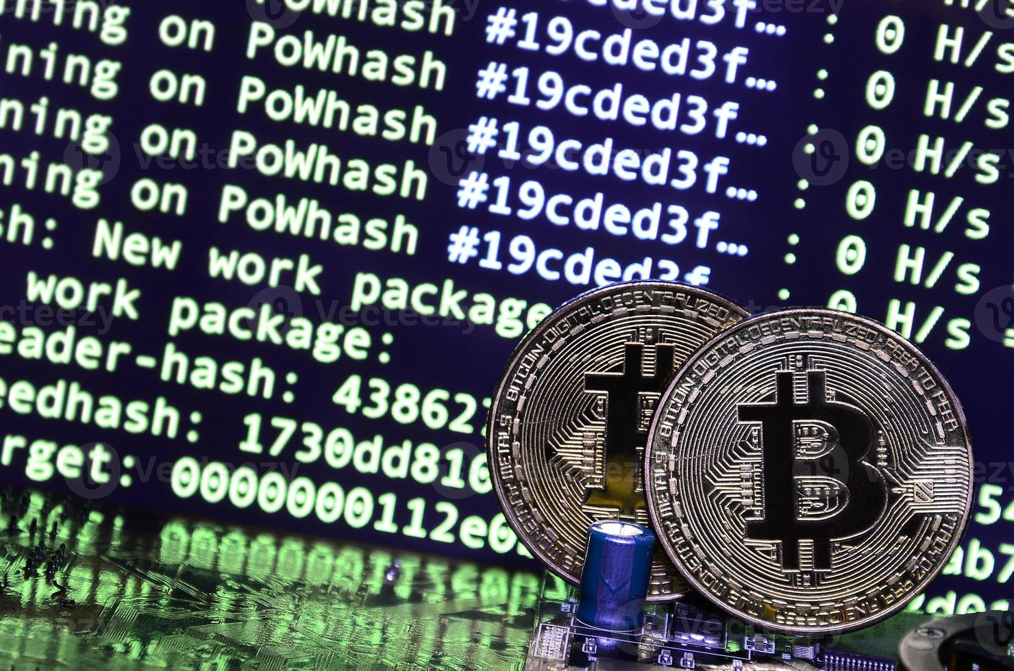 Two bitcoins lies on a videocard surface with background of screen display of cryptocurrency mining by using the GPUs photo