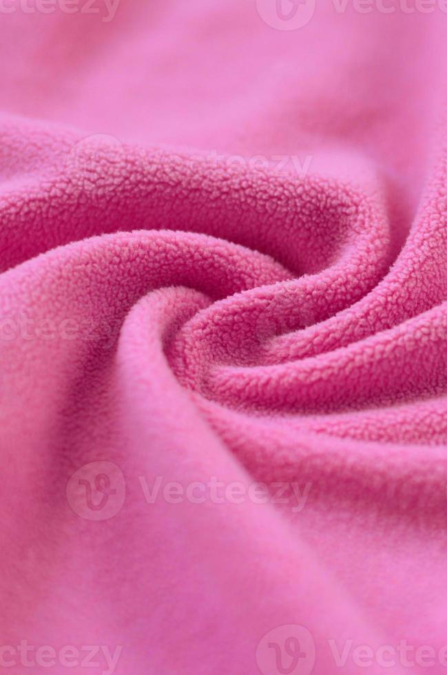 The blanket of furry pink fleece fabric. A background of light pink soft plush fleece material with a lot of relief folds photo