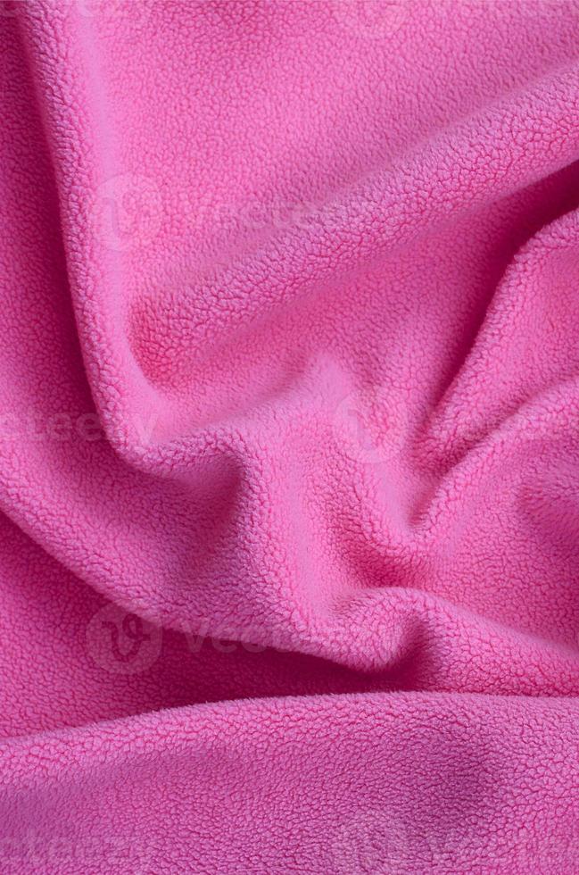 The blanket of furry pink fleece fabric. A background of light pink soft plush fleece material with a lot of relief folds photo