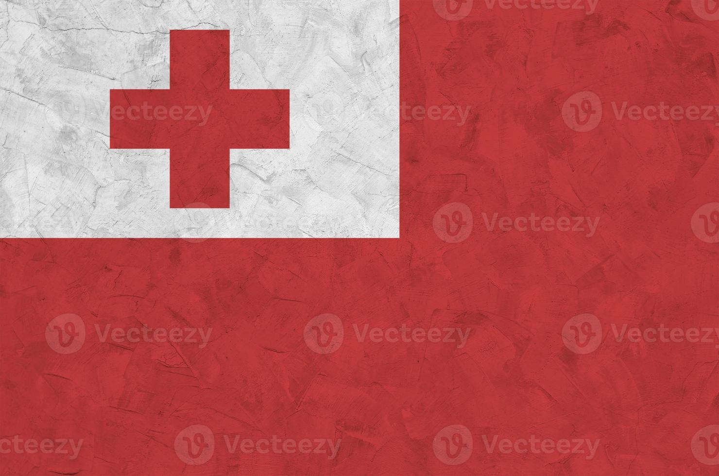 Tonga flag depicted in bright paint colors on old relief plastering wall. Textured banner on rough background photo