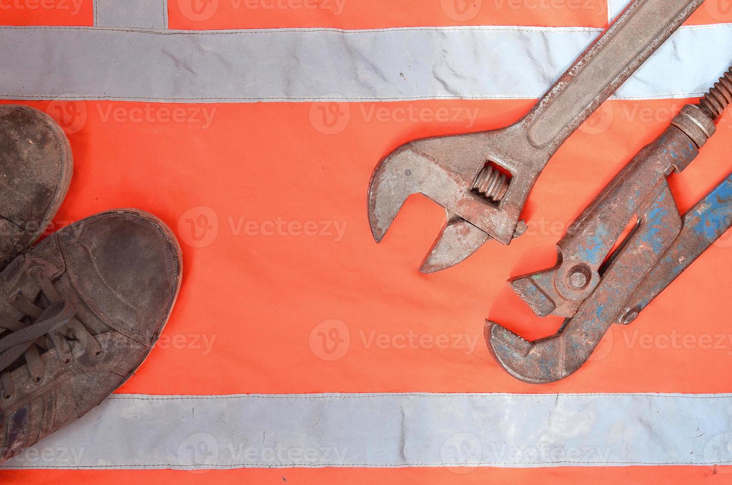 Adjustable and pipe wrenches against the background of an orange signal worker shirt photo