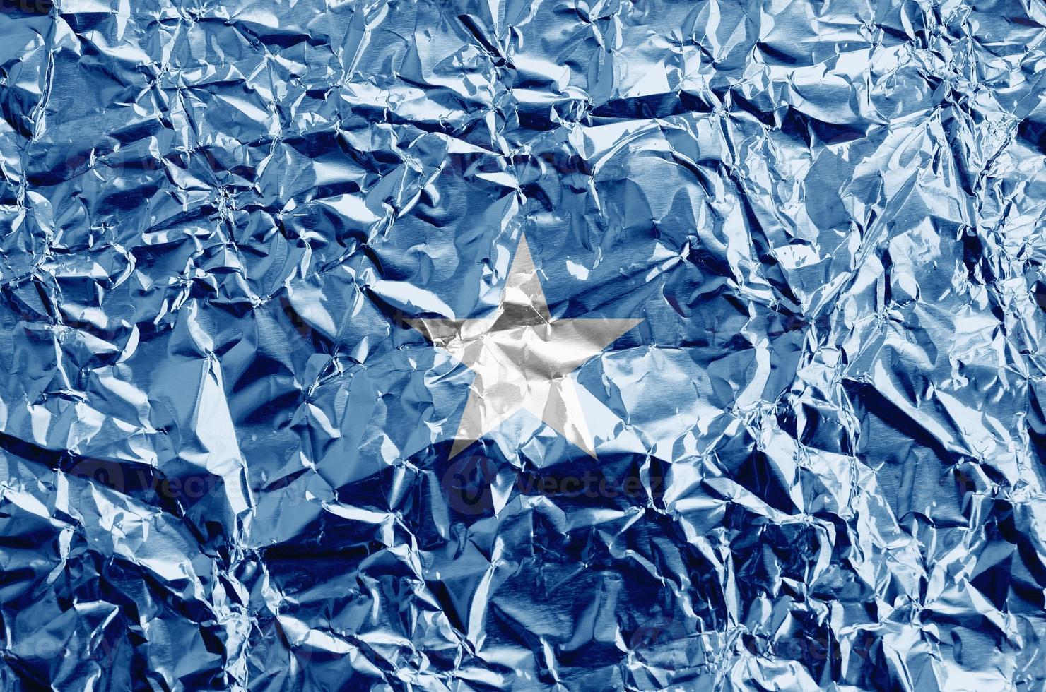 Somalia flag depicted in paint colors on shiny crumpled aluminium foil closeup. Textured banner on rough background photo