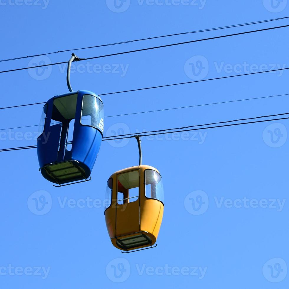 Blue and yellow passenger cable way cabins in the clear sky photo