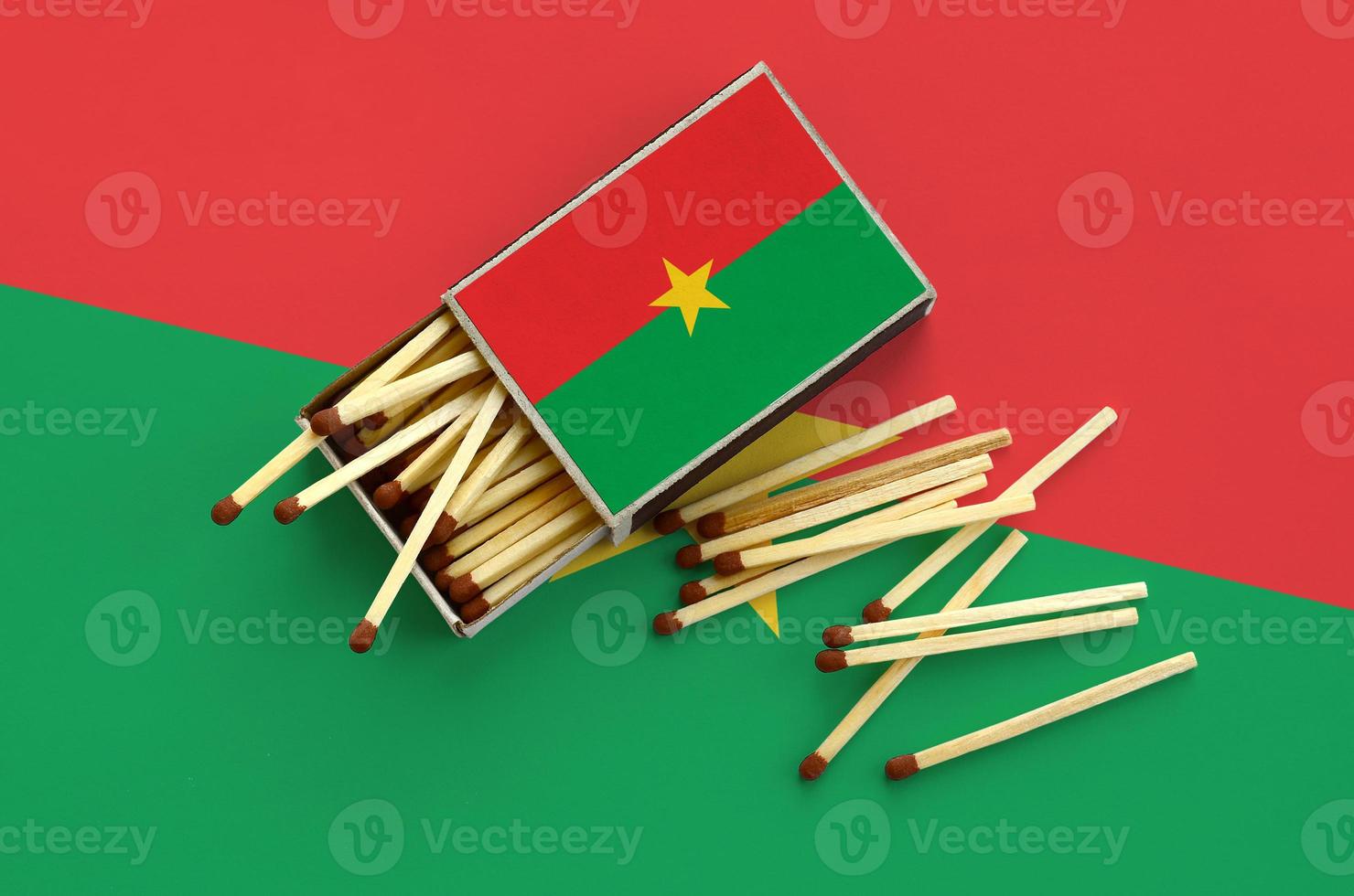 Burkina Faso flag  is shown on an open matchbox, from which several matches fall and lies on a large flag photo