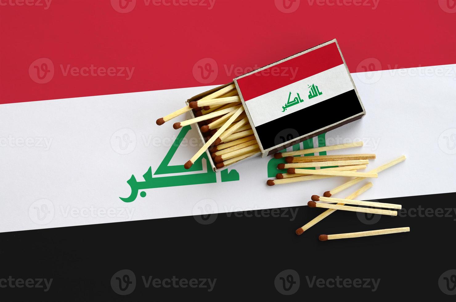 Iraq flag  is shown on an open matchbox, from which several matches fall and lies on a large flag photo