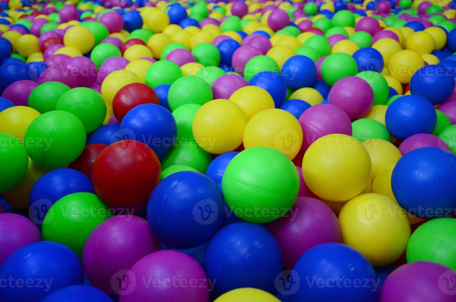 Many colorful plastic balls in a kids' ballpit at a playground. Close up pattern photo
