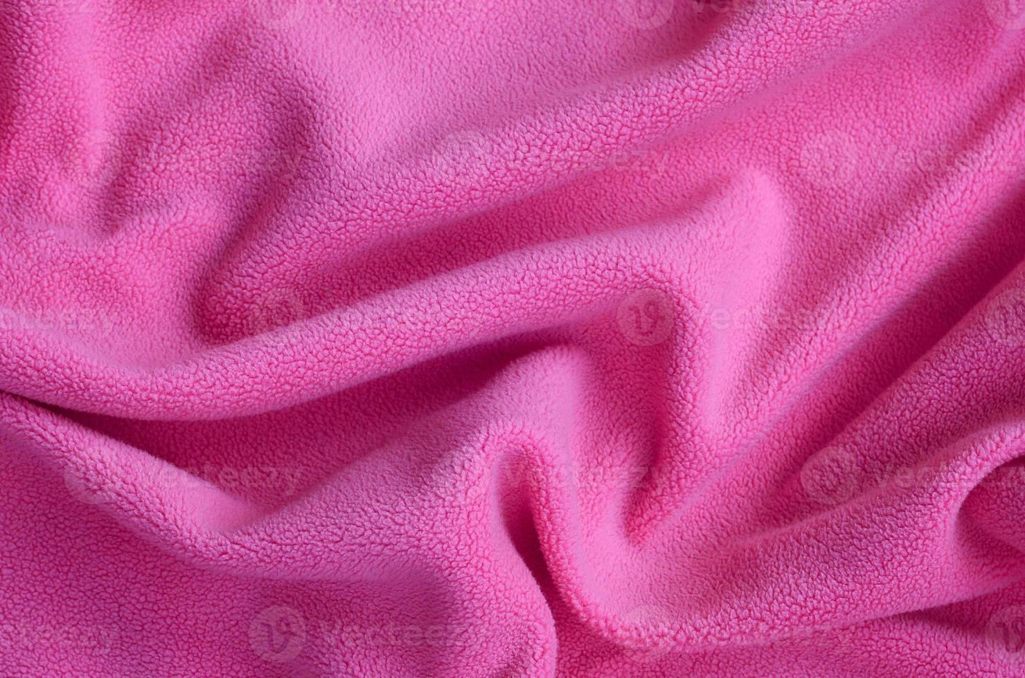 The blanket of furry pink fleece fabric. A background of light pink soft plush fleece material with a lot of relief folds photo